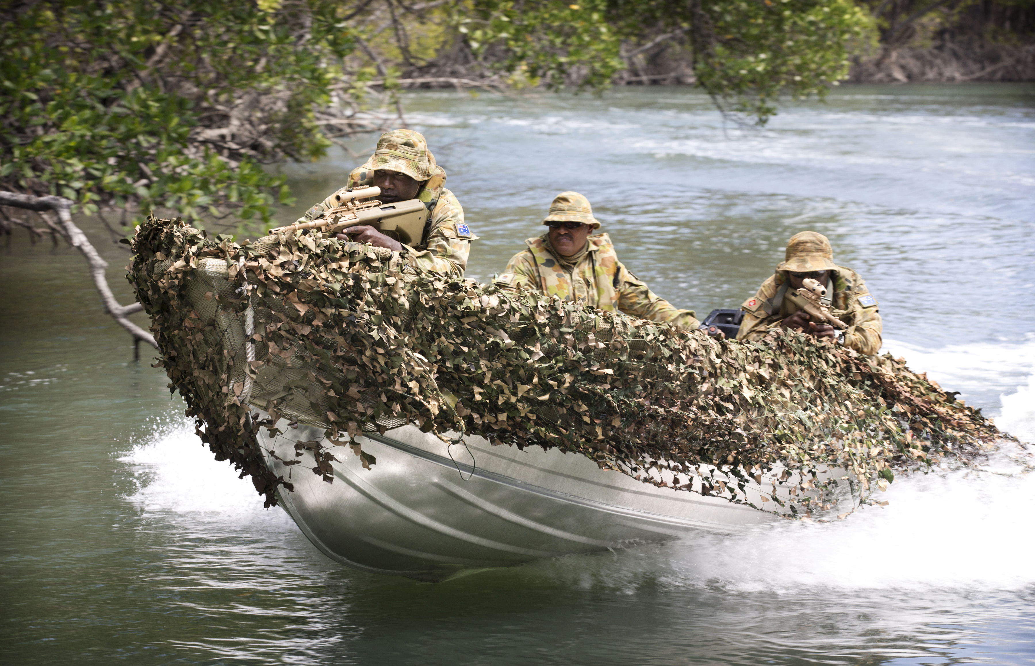 Soldiers in a tin boat with camoflage.