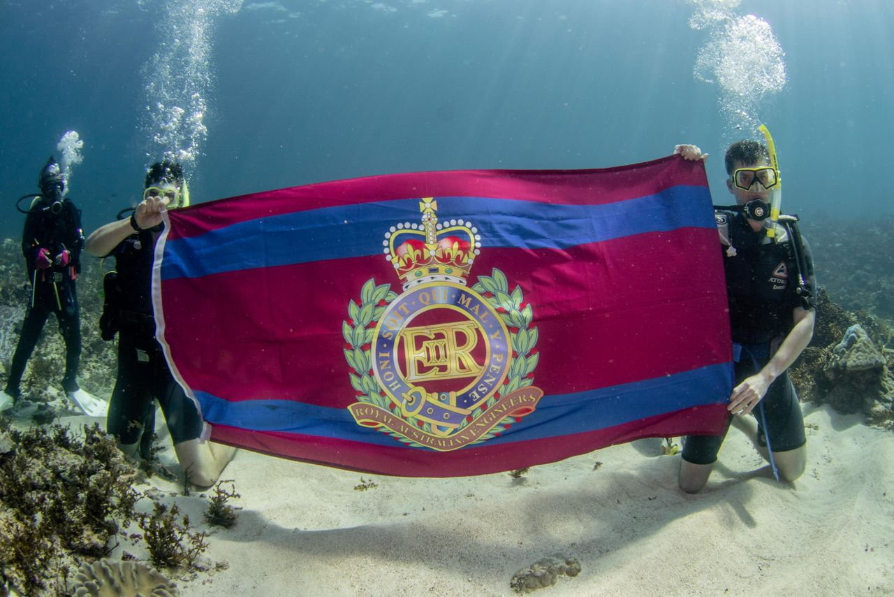 Sappers holding a flag underwater.