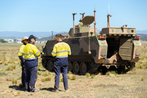 Technicians from BAE Systems Australia stand with an autonomous M113 AS4 optionally crewed combat vehicle (OCCV) at the Majura Training Area, Canberra. 