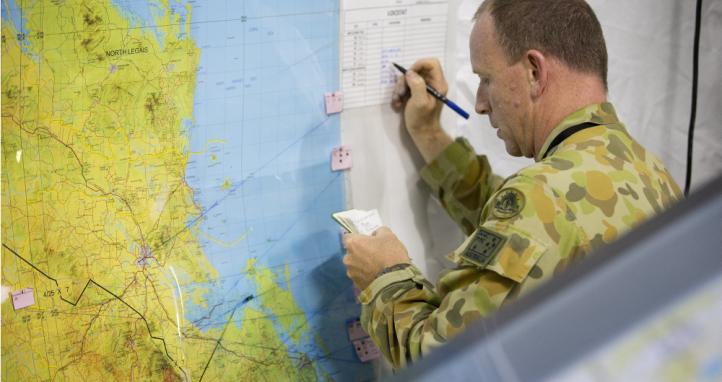 A soldier writing on a map.