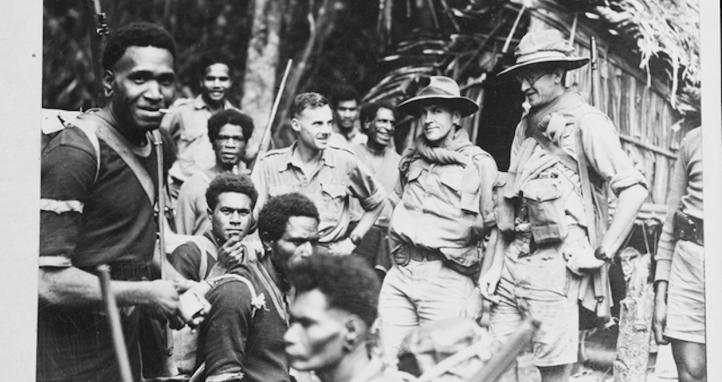 New Guinea native carriers meet Australian officers at a rest spot on the Kokoda Trail (August, 1942).