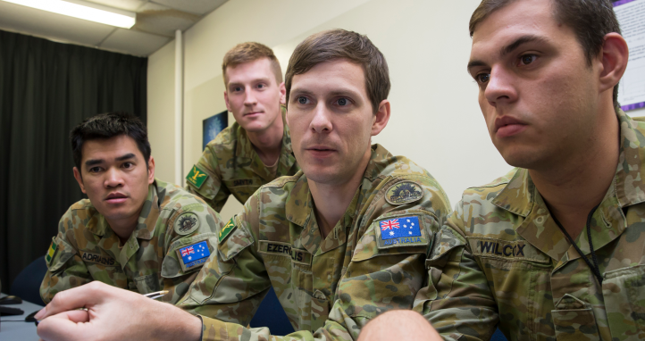 Soldiers sitting around a computer.