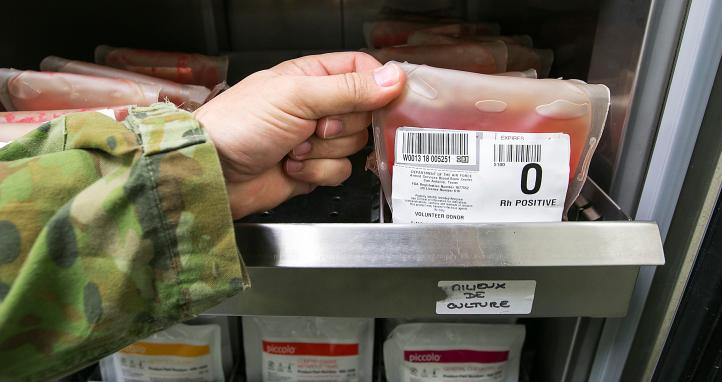 A soldier handling a blood bag from storage.