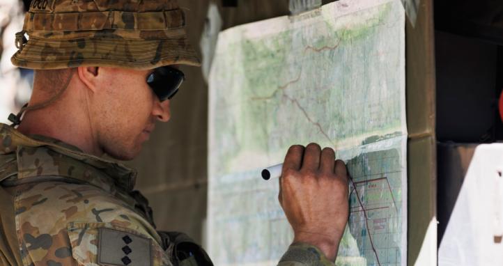 An Australian Army officer prepares a map for orders during a training exercise.