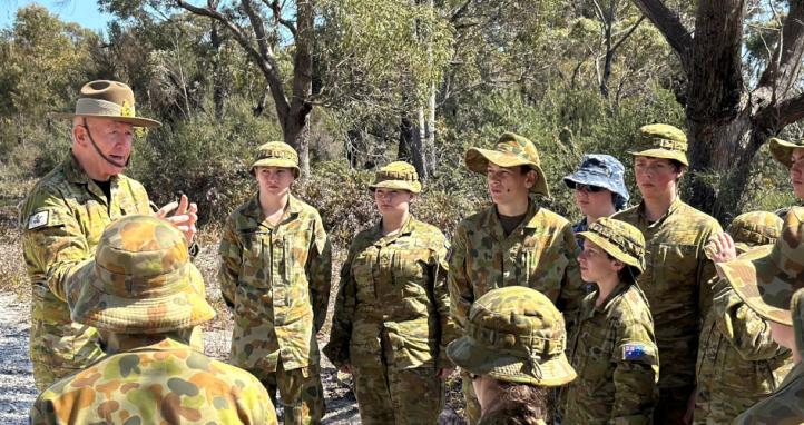 A retired general engages with Army and Air Force cadets during a field exercise.