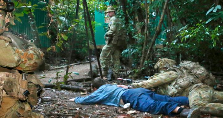 Australian soldiers take cover from 'enemy' fire after taking a prisoner during a raid on an 'enemy' camp during an exercise.