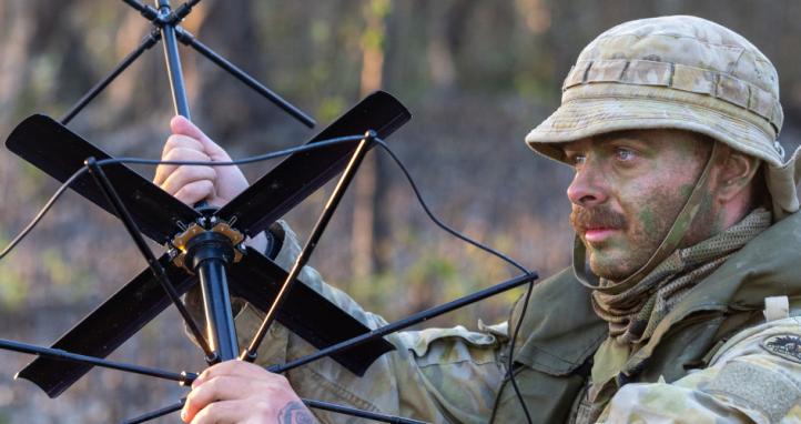 An Army signaller sets up a satellite radio antenna.