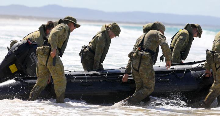 Australian soldiers pull a boat into the surf