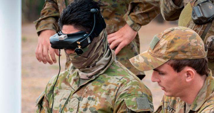 An Australian Army instructor coaches a trainee to fly a drone.