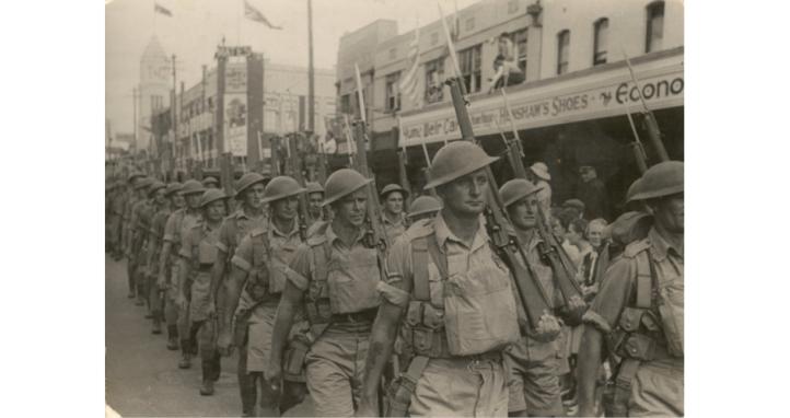 Outdoor group portrait of the 2/21 Battalion marching through Albury, New South Wales.