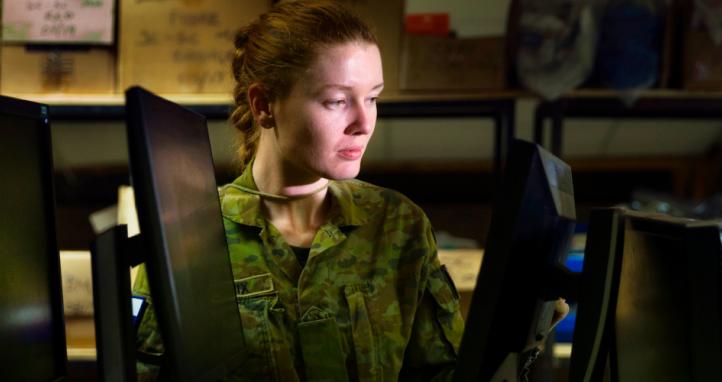 An Australian Army soldier inspects computer monitors.