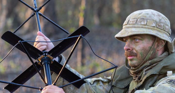 An Australian signaller sets up a satellite radio antenna.