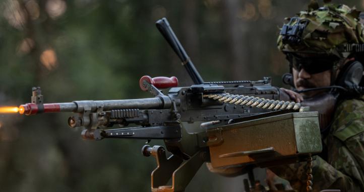 An Australian Army soldier lays down suppressing fire from the hatch of a Protected Mobility Vehicle.