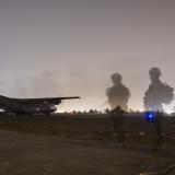 Soldiers walking onto a runway.