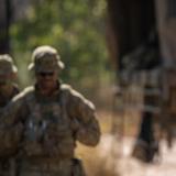 An officer directing soldiers in the bush.