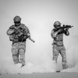 Two soldiers walking through a smoke granade.
