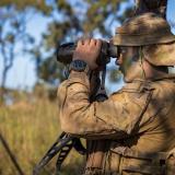 A soldier looking through binoculars.