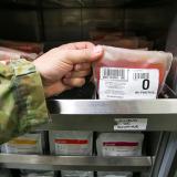 A soldier handling a blood bag from storage.