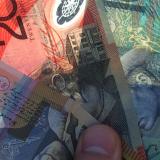 A hand fanning out Australian dollar notes.