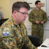 A soldier sitting at a computer.