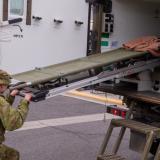 An Australian Army medic loads a stretcher into the back of an Army Ambulance.