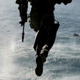 A soldier jumping from an aircraft into the sea.