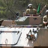 Army soldiers in three armoured vehicles.