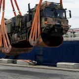 Australian Army Soldiers loading a vehicle onto a seagoing vessel with a crane.