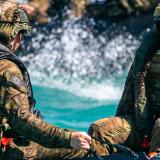 Australian Army medic with 1st Health Battalion, Private Ellouise McPherson (right) watches the water conditions while on a Zodiac Small Craft driven by the 5th Battalion, The Royal Australian Regiment during casualty winch-extraction scenarios with CareFlight in Darwin, NT.