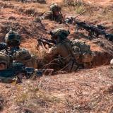 Australian Army riflemen clear an objective during a trench warfare assault training scenario.