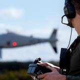 An Australian soldier operates a drone in the distance.