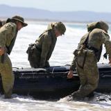 Australian soldiers pull a boat into the surf