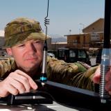 Australian Army officer Major Geoffrey Small installs a silver shield electronic countermeasure device on a vehicle.