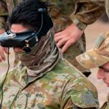 An Australian Army instructor coaches a trainee to fly a drone.