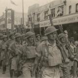 Outdoor group portrait of the 2/21 Battalion marching through Albury, New South Wales.