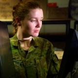 An Australian Army soldier inspects computer monitors.