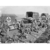 Soldiers rest by trucks on the road.