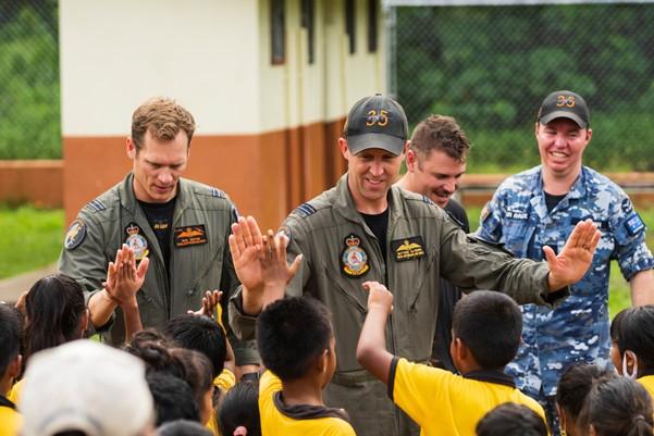 Royal Australian Air Force aviators greet students during a visit to an elementary school in Pohnpei, Federated States of Micronesia, during Operation SOLANIA